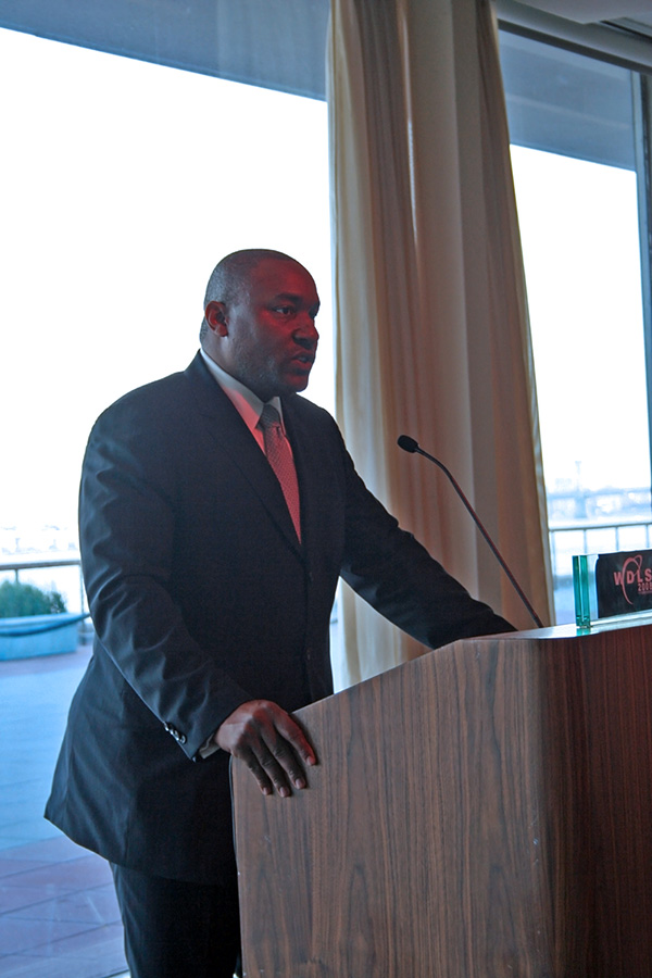 Master of Ceremony speaking at a podium at a United Nations reception dinner with conference branding on it.