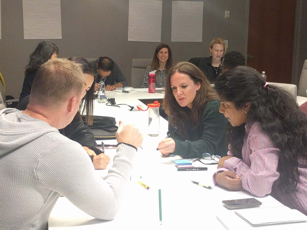 People working together at large white desks during a UX Design Jam Session