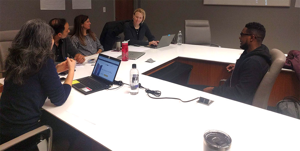 People working together at large white desks during a UX Design Jam Session