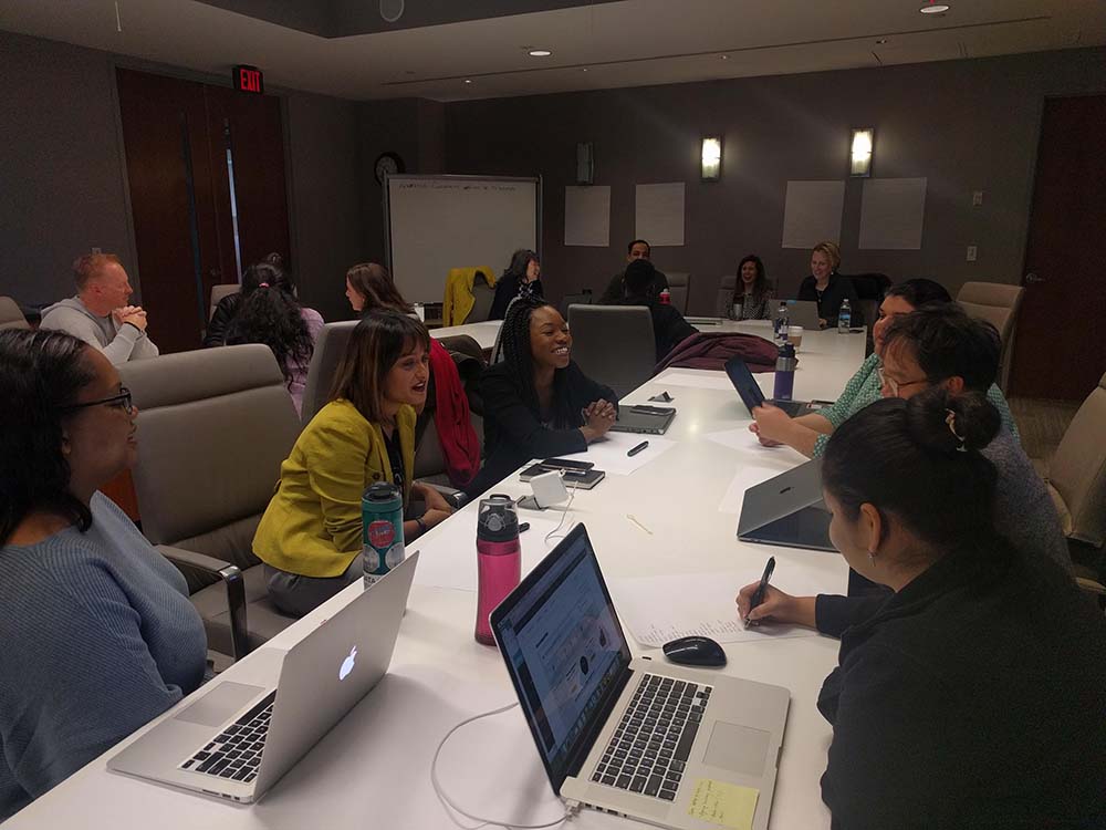 People working together at large white desks during a UX Design Jam Session